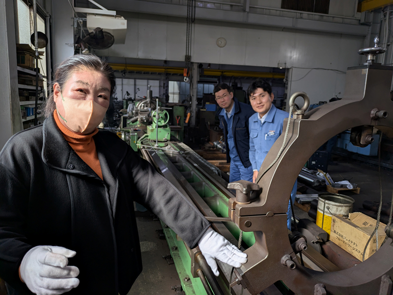 加藤工業の加藤社長（左）は丸菱製作所の戸松社長（右）が始めたアスナロを活用して、得意の長尺シャフトの旋盤加工の仕事を増やしている