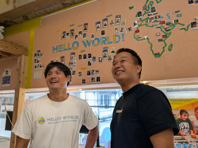 ハローワールド本社の壁には、まちなか留学で子供たちを受け入れる外国人家庭の出身国旗や世界で活躍するメンバーホストの写真が張られている。
